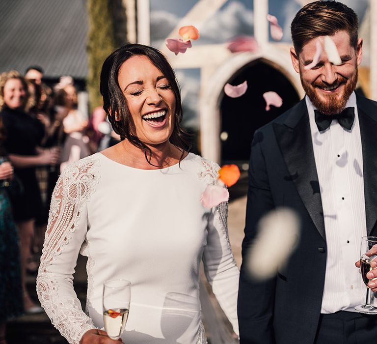 Cute confetti moment for the bride and groom in black tie 