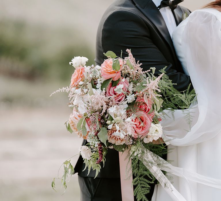 Pastel pink roses in green foliage tied with pink ribbon bridal bouquet