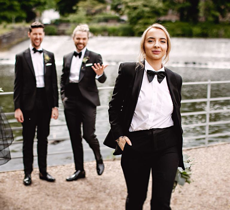 Bridesmaid with blonde hair wears black-tie suit 