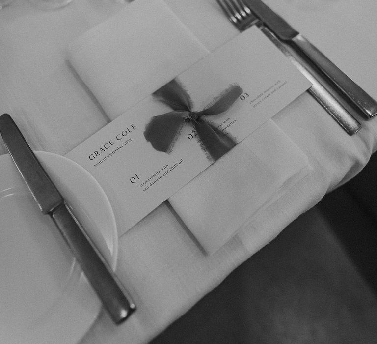 Minimalistic black and white wedding dinner menu tied with frayed silk ribbon