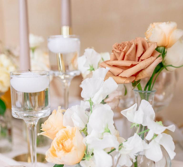 Toffee roses and white flowers decorate the wedding reception table with white candles 