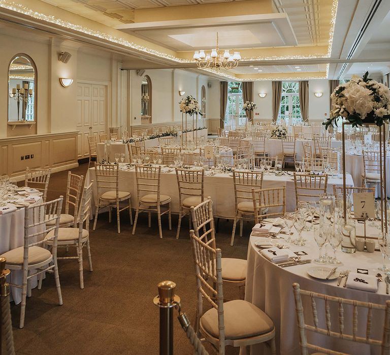 Classic white wedding tablescape with tall white flower centrepieces and table decor 