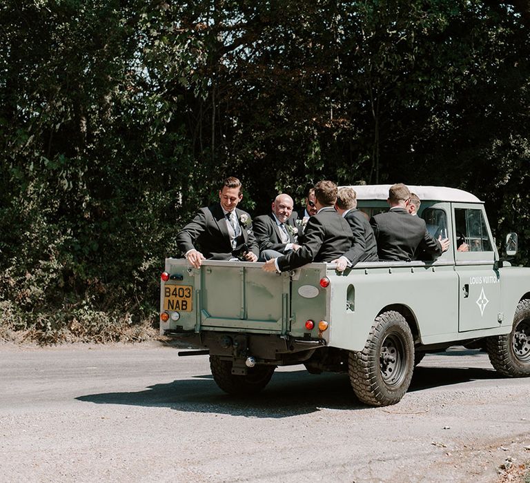 Groomsmen ride in sage green truck with a Louis Vuitton logo over to the reception 