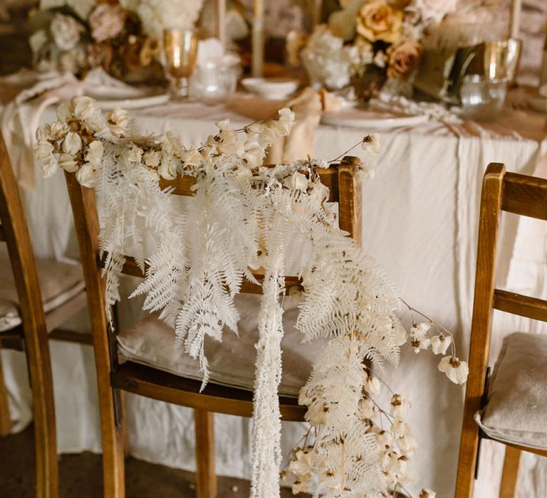 Rustic wedding chairs with white dried grass and flowers for a neutral colour palette tablescape 