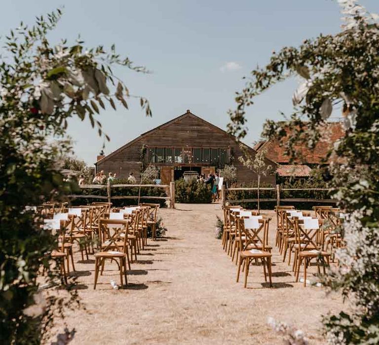 The exterior of High Billinghurst Farm outdoor ceremony space with wooden chairs and foliage 