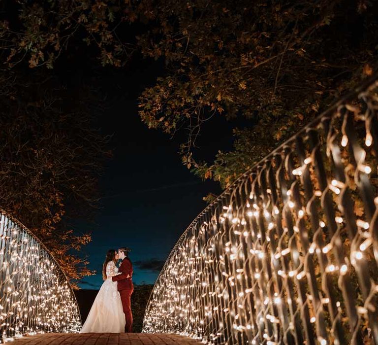 Brides kissing on bride with fairy lights at Bassmead Manor Barns wedding venue Cambridgeshire 