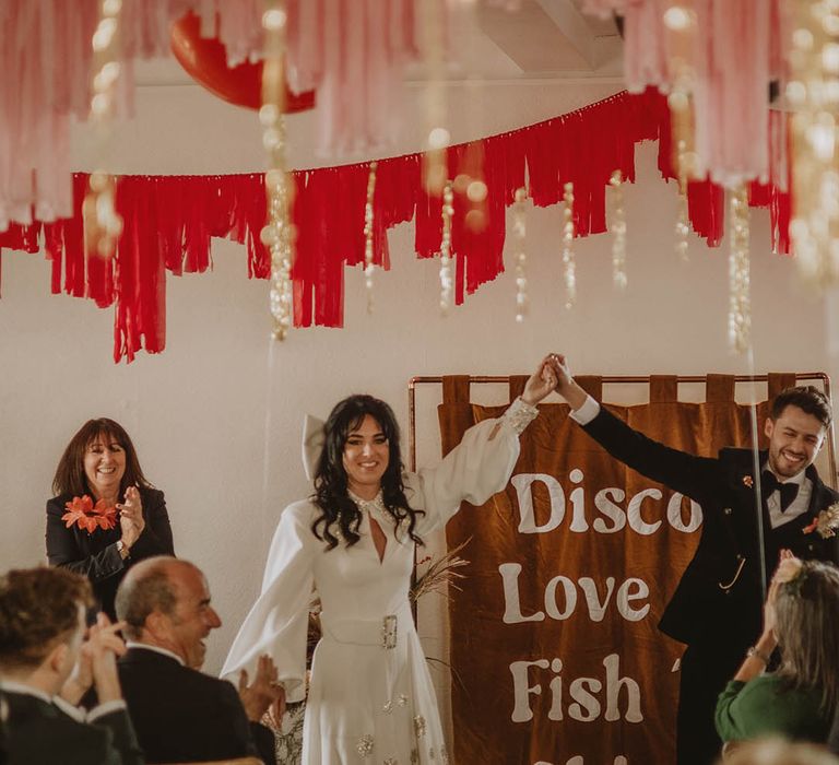 Funny brown wedding banner as altar decoration with pink, red, and gold wedding streamers and balloon decor 