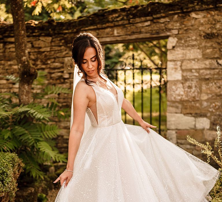 Bride in a sparkly princess wedding dress by Gabbiano twirling in Caswell House gardens 