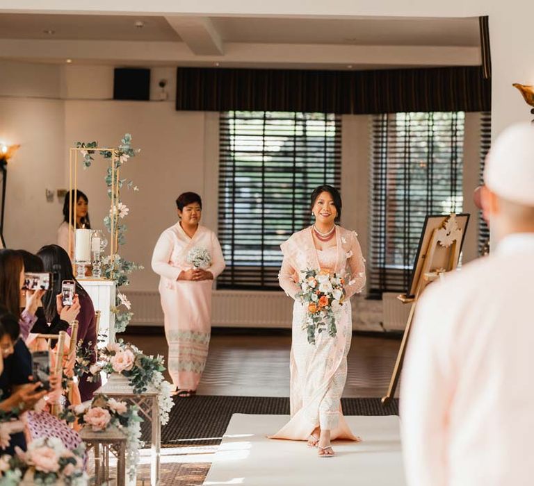 Bride in floral 3D applique pink and rose gold htamane walking down the aisle at Bron Eifion wedding venue for Burmese wedding