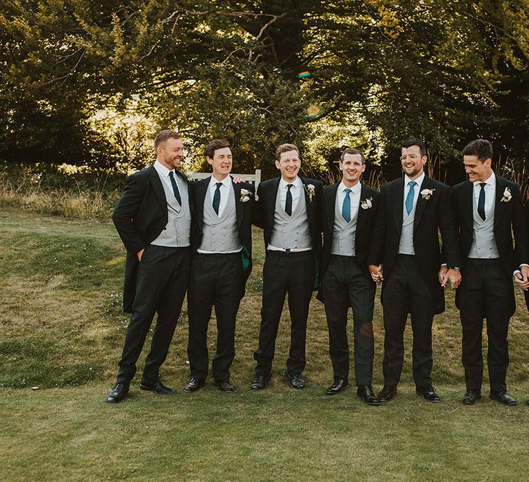 Groom and groomsmen in morning suits with pinstriped trousers and light grey waistcoats