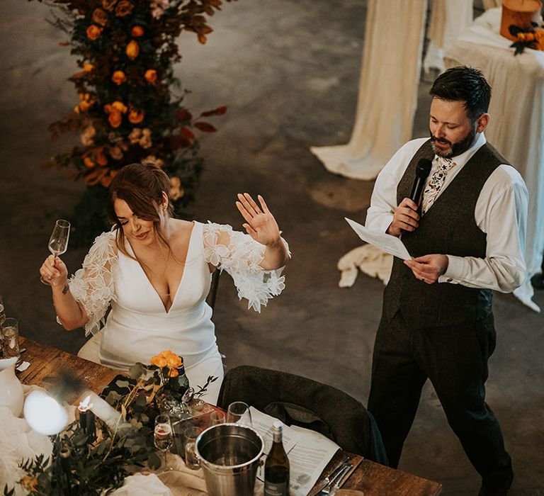 Groom delivers a wedding speech at the informal wedding with the bride laughing along 