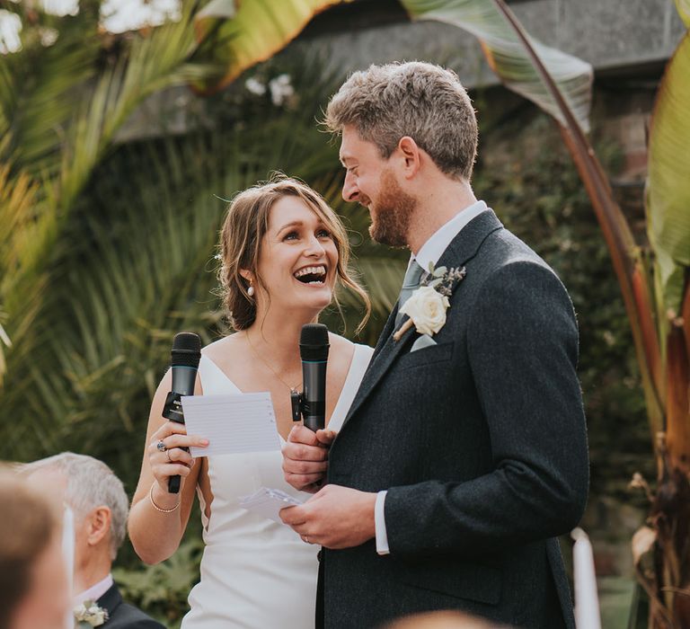 The bride and groom stand together reading out their joint wedding speech 