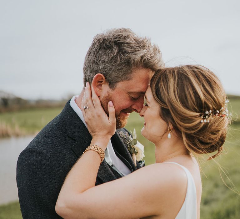 Groom in dark grey sit with the bride in a minimalist wedding dress wearing white gypsophila hair accessories 