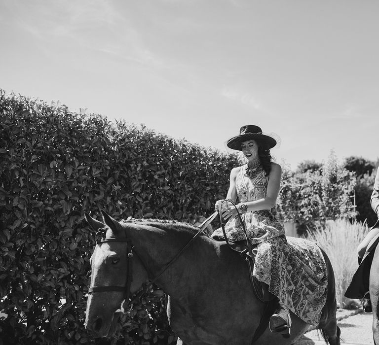 bride in boho wedding dress and father of the bride riding horseback to to wedding ceremony