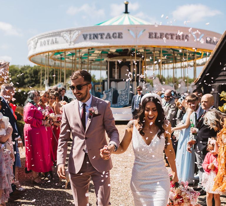 Bride in sparkly Made With Love wedding dress with groom in pink taupe suit having confetti moment 