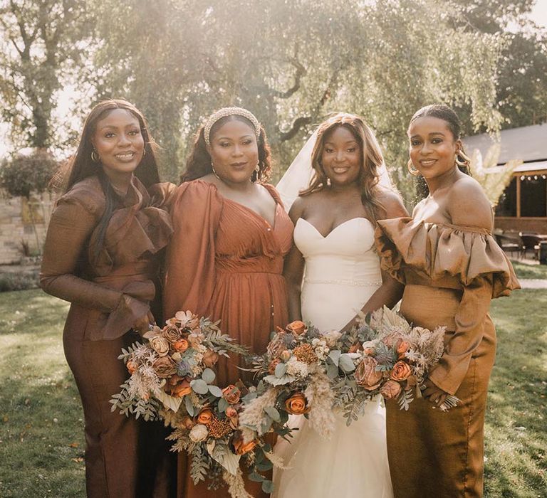 Bridesmaids wearing autumnal bridesmaid dresses in deep brown, orange and rust shades 