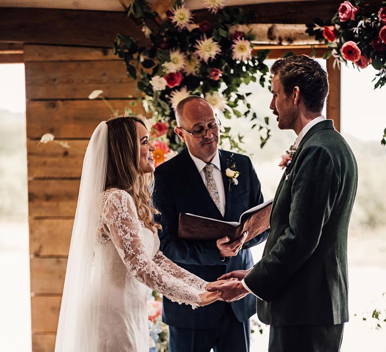 Bride and groom holding hands at their wedding ceremony led by a celebrant 