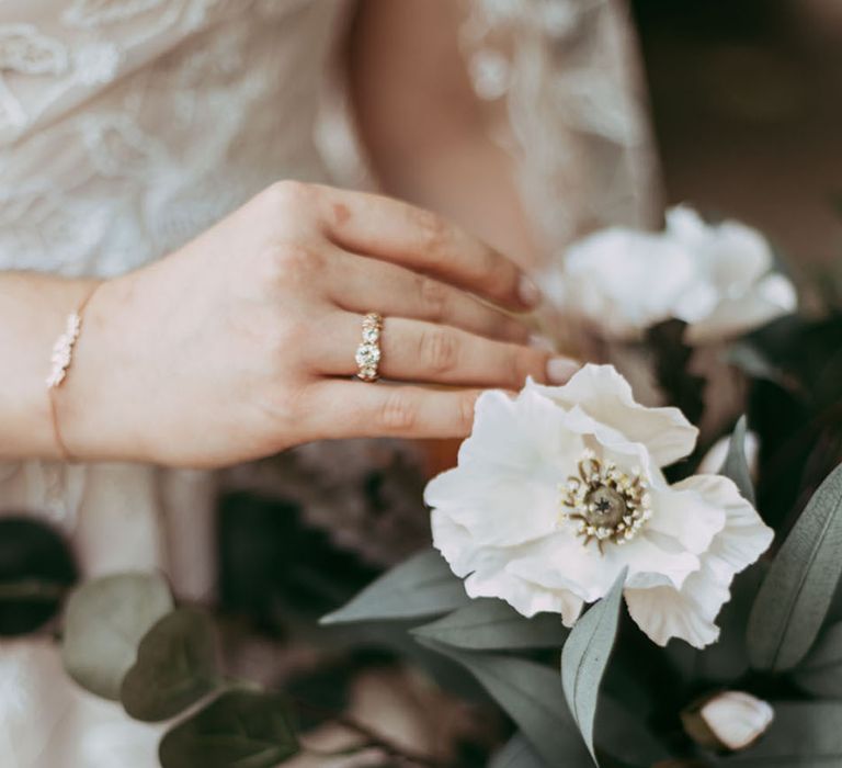 Bride wearing diamond engagement ring holding white flower wedding bouquet 