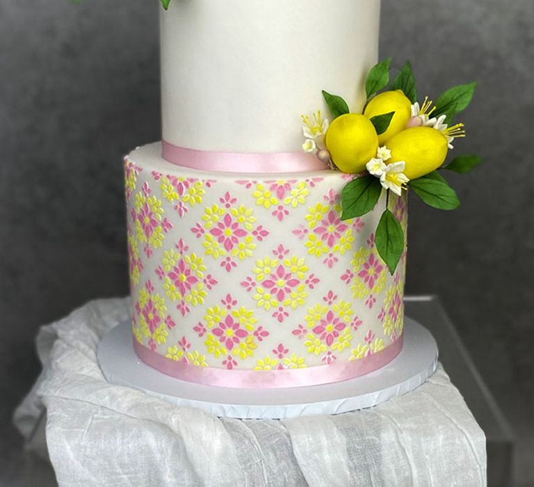 Two tier iced wedding cake with pink ribbons, yellow lemons and more 