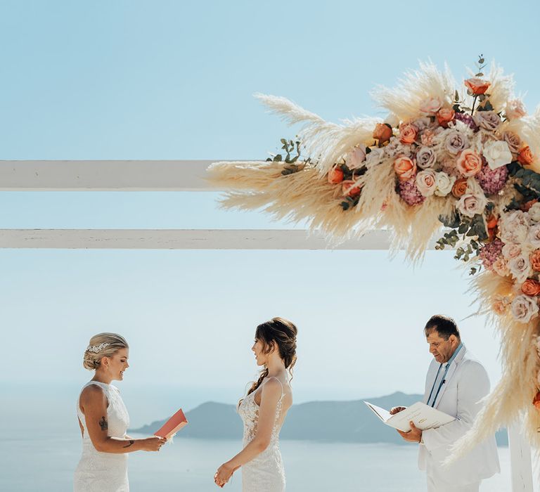 Brides exchange personalised wedding vows at Santorini destination wedding 