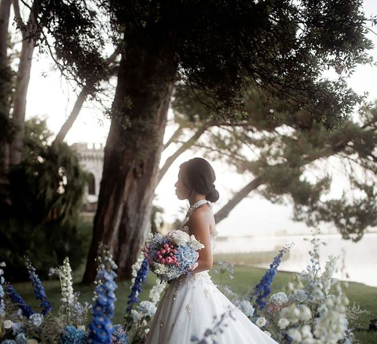 Bride walking down the aisle decorated with blue bell flowers at outdoor destination wedding 