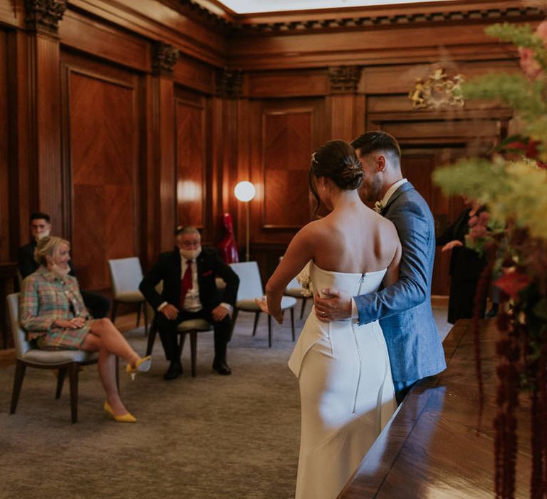 Groom embracing his bride at town hall micro wedding