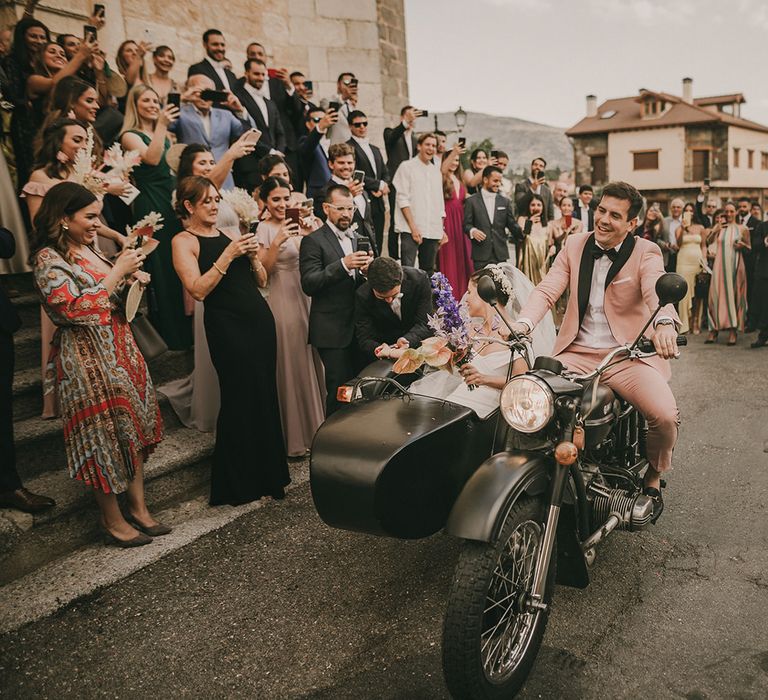 Bride and groom riding off on a motorcycle and sidecar