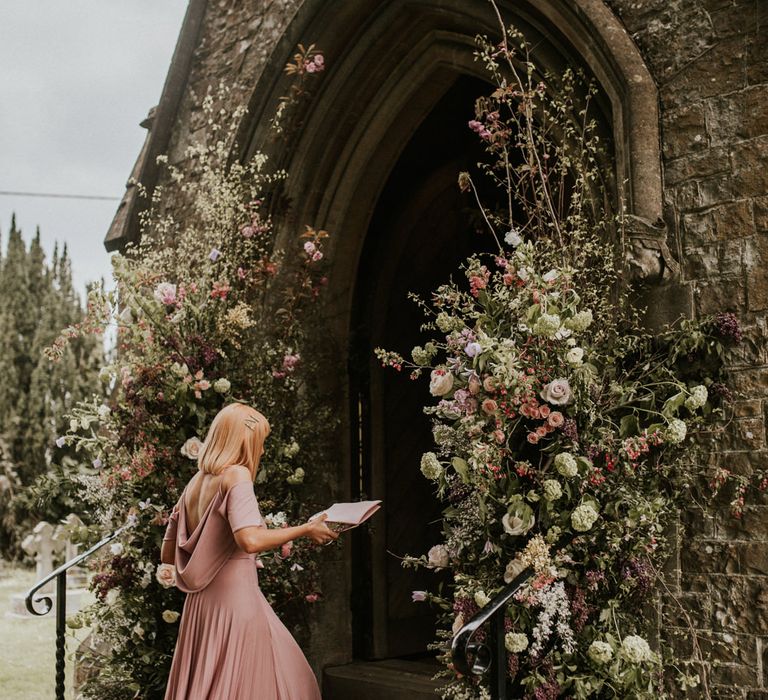 Bridesmaid in dusky pink dress entering the church 