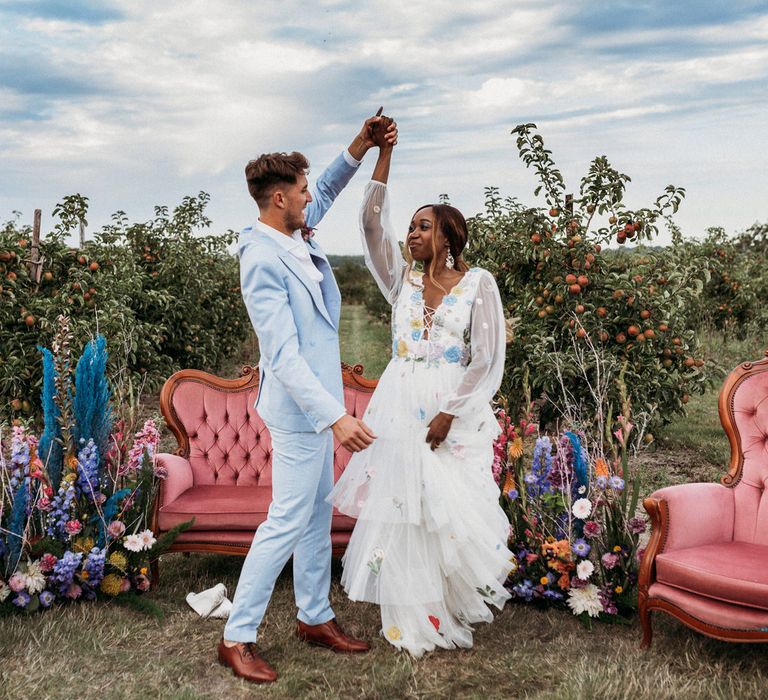 Bride in flower embroidered wedding dress dancing with her groom