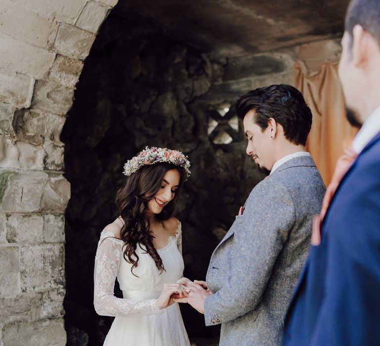 Bride places a ring on grooms finger