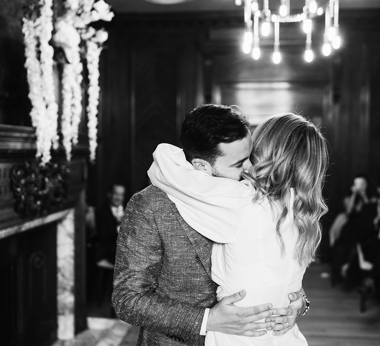 Black and white wedding day photography of bride and groom hugging at town hall wedding 