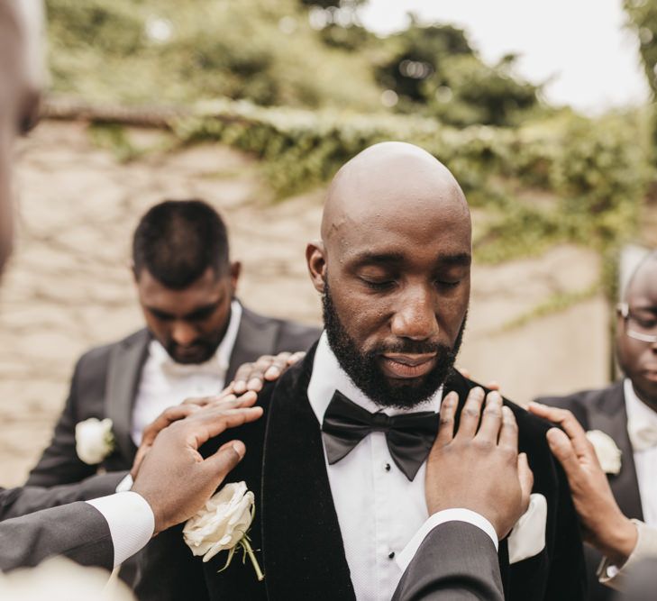 Black bearded groom in a tuxedo and bow tie with white rose buttonhole 