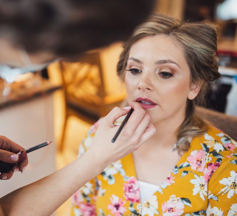 Bridesmaid in a yellow floral robe having her makeup done on the wedding morning 