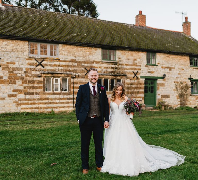 Bride & groom stand together outdoors smiling and laughing