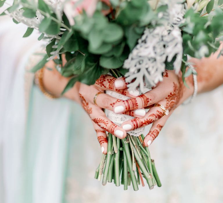 Muslim bride with henna art and white nail polish holding a pastel flower and foliage wedding bouquet 