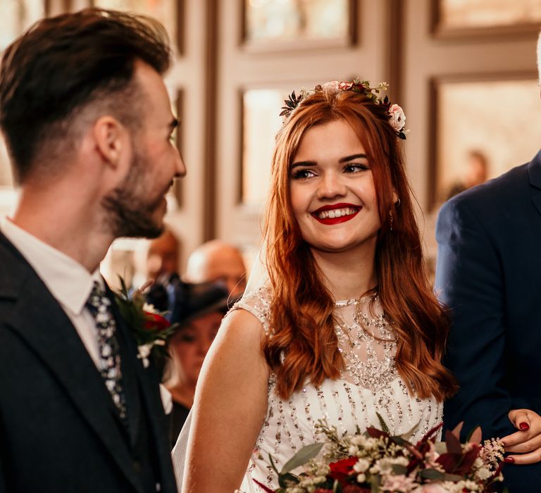 Bride walks down the aisle with her red hair in loose curls 