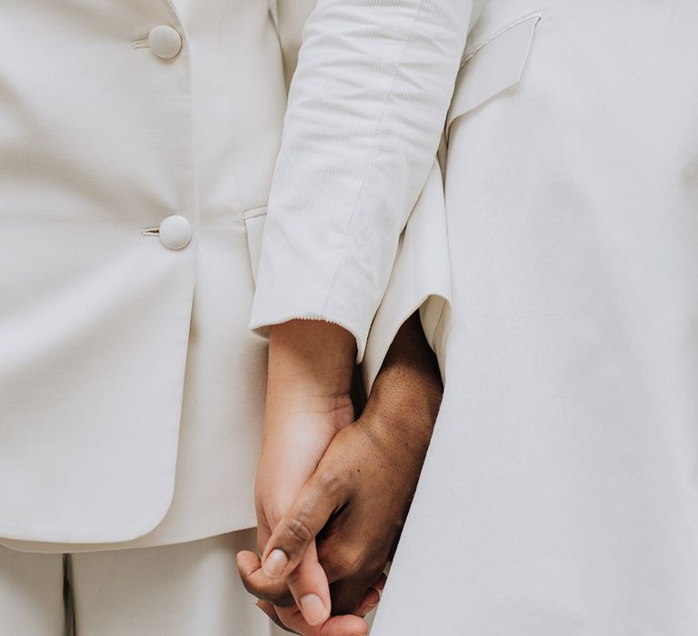 Brides holding hands in their bridal blazers