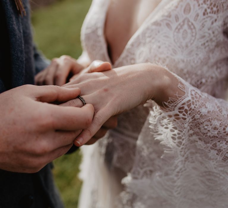 Groom places handmade ring on brides finger