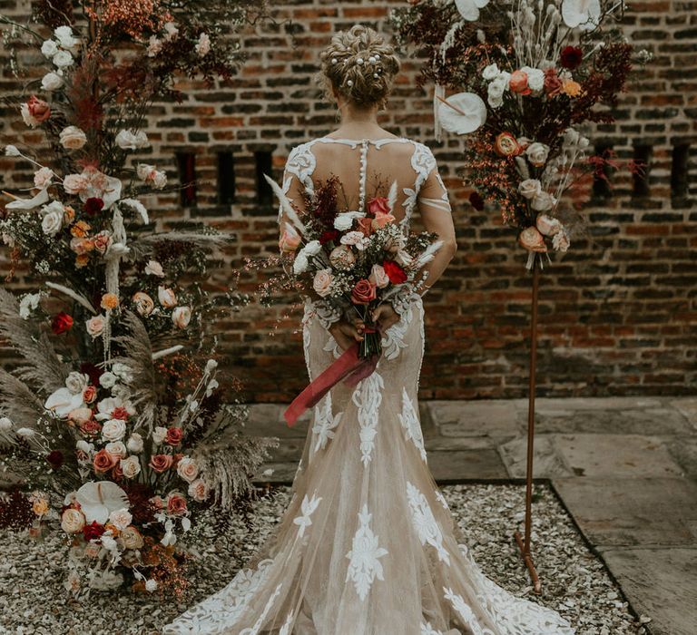 Bride with curly wedding hair up-do, wearing a mesh and embroidered white and neutral wedding dress for barn wedding