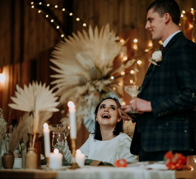 Grooms wedding speech in a navy check suit with fairy light top table backdrop 