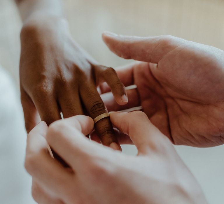 A groom places the ring on the bride's finger. 