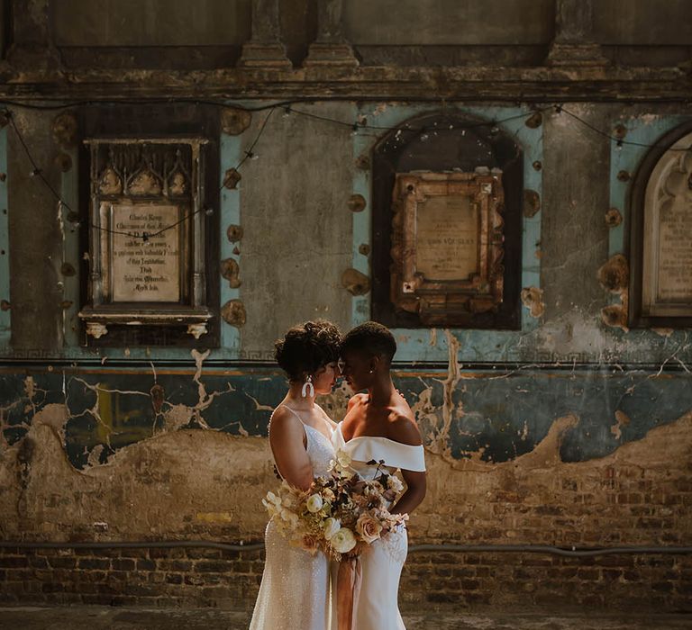 Portrait of two brides in a sparkly wedding dress and fitted off the shoulder gown with puddle trains 