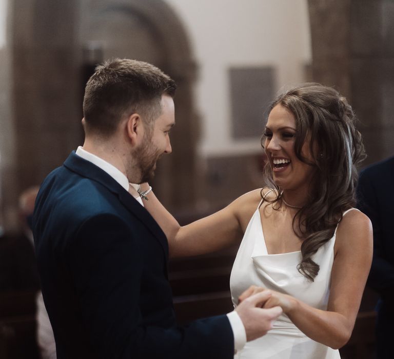 Bride and groom holding hands and smiling as they get married