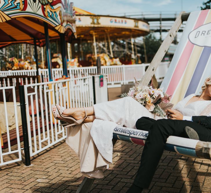 Bride and groom sitting in a giant pastel coloured deck chair at Dreamland Margate 