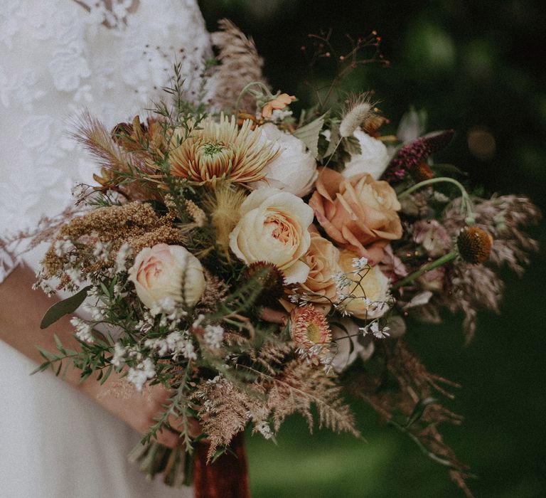 Burnt orange themed wedding bouquet with roses, fern and mixed florals and burgundy ribbon for garden wedding