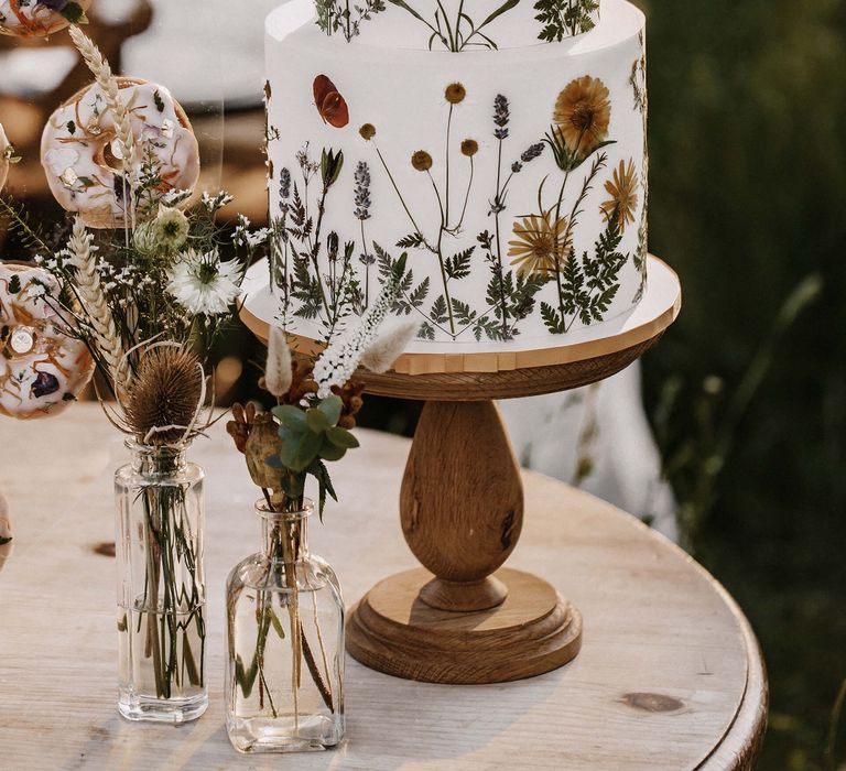 Flower pressed wedding cake with edible flowers on a wooden cake stand 