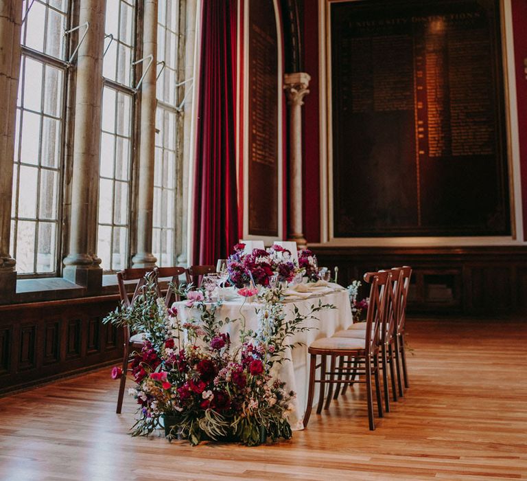 Intimate wedding reception table with deep red and pink wedding flower centrepieces and arrangements 