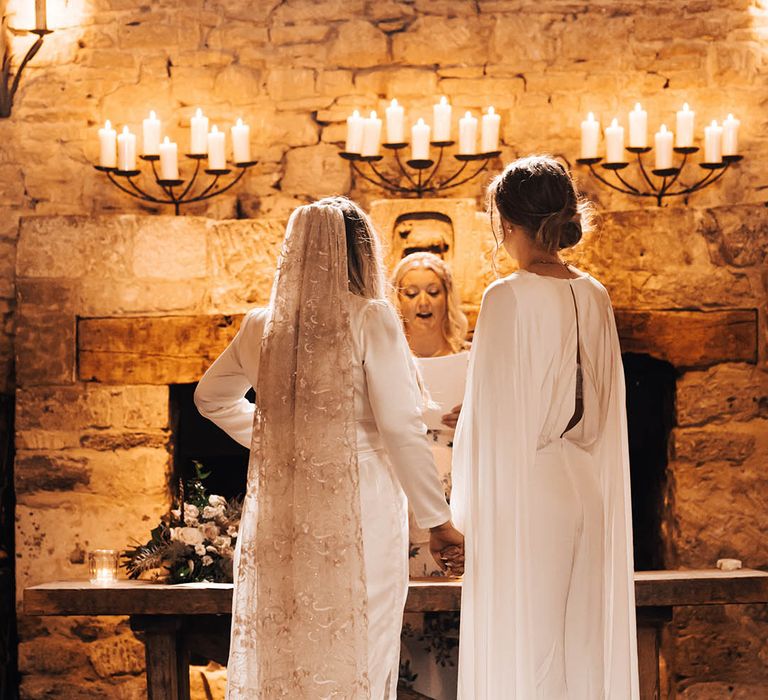 Brides look lovingly at one another on their wedding day during ceremony