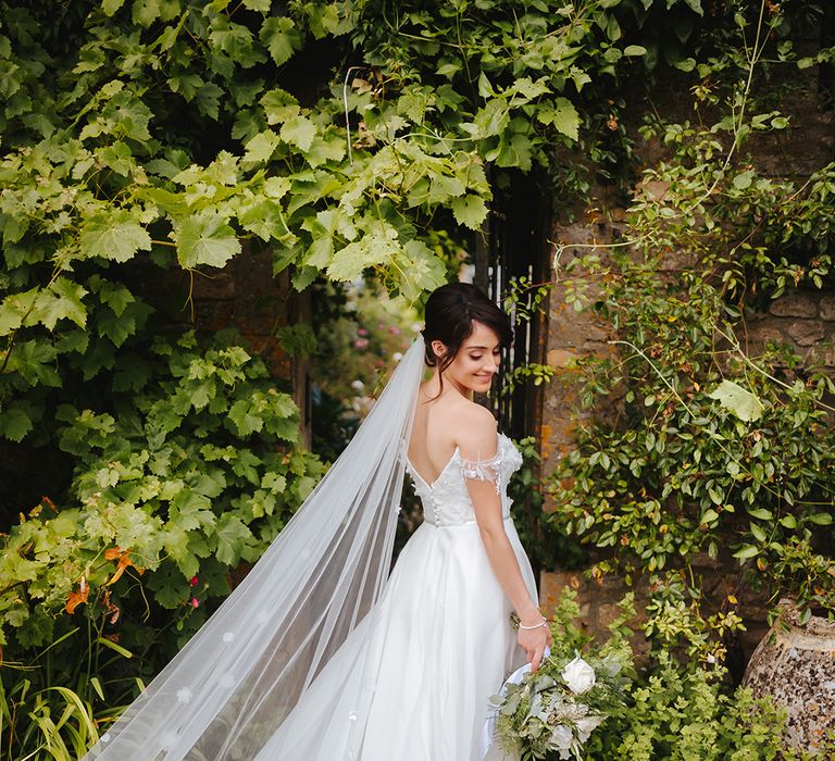 Bride wears bespoke Suzanne Neville wedding gown complete with Martina Liana veil finished with appliqué detailing 