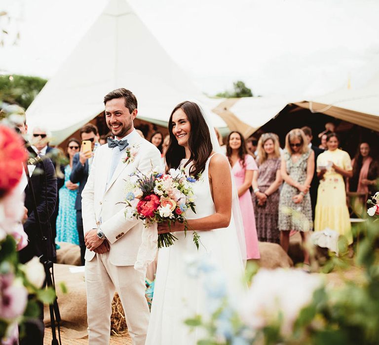 Bride & groom stand together on their wedding day outdoors